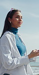 Ocean, smile and woman with phone, internet for online chatting and travel for summer holiday. Happy, walking and person with tech for social media, vacation and connection for tourism and network