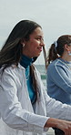 Women, friends and bike on promenade at beach with smile, ride and bonding on seaside vacation. People, happy and outdoor on holiday for cycling, memory or tourism with bicycle by ocean on getaway