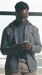 Phone, typing and black man in office with texting, networking or communication on mobile app. Technology, reading and African male person with cellphone for online email with contact in workplace.