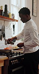 Kitchen, cooking and chef with olive oil by stove for meal prep, cuisine and recipe at restaurant. Hospitality, catering and black man with ingredients for dinner, lunch and food for culinary service