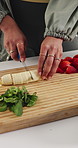 Person, hands and cutting with banana in kitchen for fruit smoothie, meal prep or detox in home. Nutritionist, diet and slicing with natural organic food for potassium, nutrition or vitamins on board