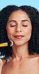Shine, brush and woman in studio, makeup for beauty and dermatology on blue background. Tools, facial foundation and person with aesthetic, wellness and product for glow, skincare and cosmetics