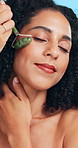Skincare, facial roller and woman in studio for natural, beauty and lymphatic drainage massage. Relax, health and female person with jade stone cosmetic tool for blood circulation by blue background.