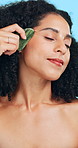 Woman, skincare and massage in studio with gua sha, beauty routine and blood circulation benefits. Person, relax and cosmetic tool for lymphatic drainage, wellness and dermatology on blue background.