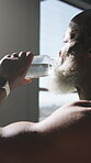 Fitness, drinking water or mature man in gym with break, workout fatigue or hydration in intense practice. H2o, burnout or black person with bottle, training pause and recovery for performance goals.