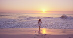 Woman, sunset and back view on beach for travel, splash and vacation wellness outdoor. Sky, space and female person on ocean shore for waves, fresh air and break on getaway trip for self care