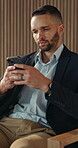 Phone, reading and text message with business man in office for break, communication or response. App, social media and texting with serious employee in workplace lobby for mobile or online chatting