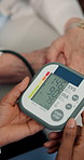 Person, hands and blood pressure with machine for hypertension, elderly care or exam in home. Senior patient, nurse or doctor monitoring heart rate for medical diagnosis, checkup or test results