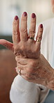 Hands, arthritis and old woman in home with wrist pain, massage or symptoms for carpal tunnel syndrome. Elderly person, joint inflammation and stretching with discomfort, osteoporosis or health issue