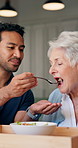 Caregiver, feeding and food with old woman at house for support, assistance and healthy lunch. Nurse, talking and senior person with salad for nutrition, assisted living and helping hand for wellness