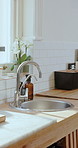 Empty, faucet and kitchen with equipment in home for meal prep, clean and culinary utensils. Design, furniture and rustic interior with flowers, storage and kitchenware for house decor and appliances
