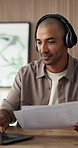 Headphones, paperwork and man with laptop in creative agency, playlist and planning for brand post. Reading, smile and social media manager with tech for research, trends report and dancing to music