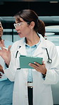 Doctor, woman and team in hospital with tablet, medical research and conversation for test results. People, walk and talk in clinic with tech, healthcare discussion or collaboration for patient care.