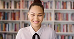 Face, student and woman in library for education, university scholarship and future development. Portrait, bookshelf and happy person in college with confidence for learning, smile or pride in Brazil