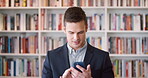 Phone, reading and man in library for online, communication and research for books or author news. Typing, scroll and professional writer with information, about us and website for literature review