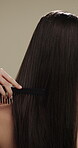 Hands, beauty and woman with comb for haircare, healthy shine and hairstyle maintenance. Back, person and styling tool on studio background for scalp stimulation, growth benefits and grooming routine