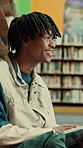 Man, student and reading in library with books for learning, education or study material. Person, academic scholar or learner with textbook, novel and smile for literature research at university
