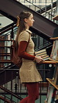Woman, college and walking in library with books for learning, education or study material. Person, academic scholar or learner with textbook, novel and knowledge for thesis research at university