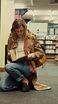 Woman, reading and student with book in library for university education, knowledge or thesis. Female person. academic or learner studying with shelf, notebook or textbook for literature in college