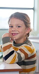 Education, face and smile of girl in classroom for child development, future or growth. Knowledge, learning and study with happy student at desk in school for academic curriculum or syllabus