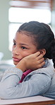 Bored, education and girl child at desk in classroom for development, future or growth. Learning, listening and thinking with student at elementary school for course, lesson or study fatigue