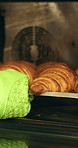 Croissant, oven and hand with glove in bakery, small business and entrepreneur with culinary skills. Catering, stove and person with mitt for thermal protection, food production and pastry order