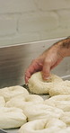 Chef, hands and bagel dough in kitchen with sesame seeds, man cooking food and restaurant cuisine. Person, grains and ingredients in bakery with container, meal prep or gluten free bread roll recipe.
