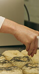 Baking, rolls and sesame seeds with baker woman in kitchen for preparation or production. Cooking, pastry and sprinkle with mature chef at counter in commercial bakery for ingredients or recipe
