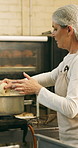 Boiling, bagel and woman with dough in kitchen, small business and dessert prep with culinary skills. Baker, stove and mature person with recipe for food process, catering and pastry order in bakery