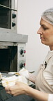 Baking, oven and woman with bread in bakery, small business or baker with culinary skills in kitchen. Sourdough, removal and mature person with tray, serious and food prep for order and catering