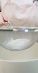 Baking, bowl and flour with hands of chef in kitchen for ingredients or recipe preparation. Process, sieve and sift with baker at work for production of bread, food or pastry as catering professional