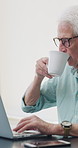 Coffee, laptop and mature man in home office, thinking or remote work with investment project. Freelancer, drink or person typing on computer in house for financial email, decision or problem solving