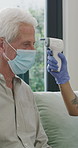 Discussion, mask and thermometer with nurse and elderly man in home with notes and checkup. Clipboard, ppe and temperature with caregiver and senior patient in apartment for medical diagnosis chat