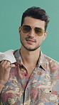 Face, fashion and sunglasses with man in studio for summer aesthetic, apparel or holiday outfit. Clothing, confidence and shades with person on green background for getaway, travel or vacation