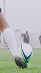 Rugby ball, foot and person on field with kick, start game or winter match in competition. Sport, player and football on tee for challenge, score conversion or accuracy practice with fitness on grass