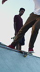 Men, ramp and feet with skateboard for exercise, extreme sports and practice with friends. Skateboarder, training and group at skatepark for competition, hobby and balance outdoor with blue sky