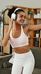 Woman, headphones and dancing in home with fitness, streaming service and happy in living room. Girl, dancer and listen to music, rhythm and audio subscription with exercise for wellness at apartment