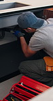 Plumber, kitchen and man with wrench, maintenance and repair with equipment in apartment. Plumbing, person and tools for pipe installation in home improvement, inspection and fixing drainage system