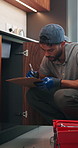 Writing, plumber or man with clipboard in kitchen, pipeline maintenance or valve corrosion inspection. Checklist, evaluation or handyman with leak report in home, filter system installation or repair