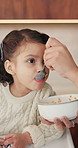 Cereal, feeding and girl in chair with building blocks for child development or growth. Food, learning and motor skills of daughter with parent in home kitchen for family, support or wellness