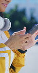 Hands, phone and girl typing outdoor in city for music search, communication and social media. Teen person, technology and connection for app, website and scroll online with headphones in road
