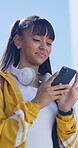 Smile, phone and girl typing outdoor in city for location search, communication and social media. Teen person, technology and connection for maps app, website or scroll online with headphones in road