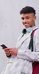 Face, phone and teen boy outdoor in city for music search, communication and social media. Happy person, technology and connection for app, website and scroll online with headphones by space on wall