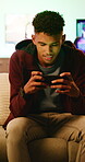 Phone, smile and teen gamer in home with internet connection, streaming and app online. Male person, happy user or technology with typing for website search, gaming or watching to relax in house