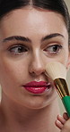 Beauty, makeup brush and woman in studio with glow, foundation or facial coverage for shine. Cosmetics, apply and person with tool for makeover, change and aesthetic with self care on background