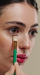 Beauty, makeup and woman with brush in studio for  concealer, glow or facial coverage with blend. Cosmetics, apply and person with tool for makeover, change and aesthetic with self care on background