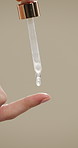Woman, hands and pipette for skincare with beauty, serum or product for shine on studio background. Natural cosmetics, female person with dropper for hyaluronic acid, skin glow or dermatology