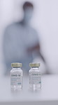 Covid, vaccine and vial bottle in hospital for healthcare, virus prevention and medical innovation. Person, coronavirus drugs and medicine in glass container for infection control, immunity or safety