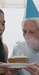 Birthday cake, old man and daughter to blow candles, house and celebrate milestone in retirement. Senior parent, happy woman and face with smile for visit, bonding and event in family home with love