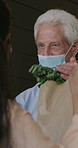 Grocery, delivery and old man at door with mask, customer service and safety for infection control. Senior person, courier worker and food package in home with PPE, virus prevention and regulations.